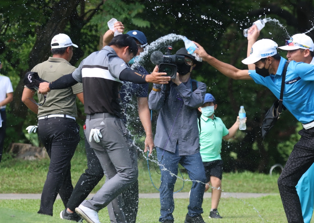 高雄公開賽職業冠軍李玠柏在果嶺上接受好友灑水慶祝。