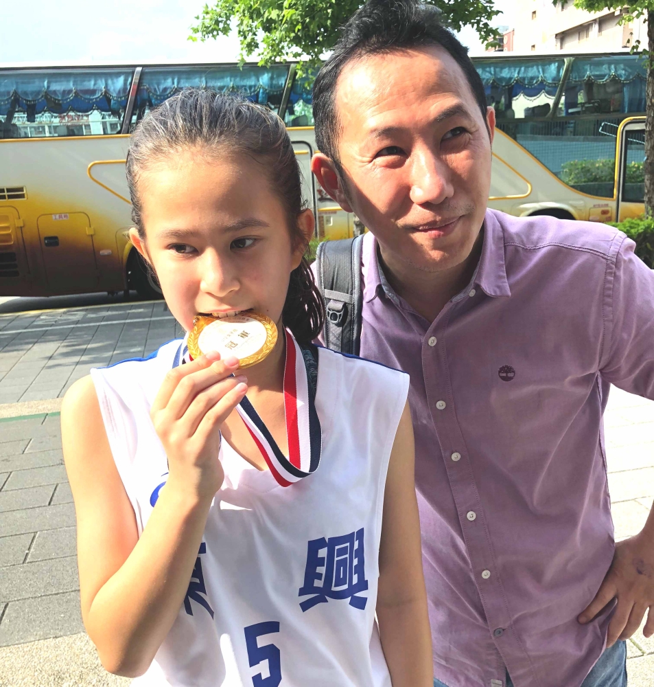 混血小正妹康珞慈與爸爸分享生涯第一面金牌。