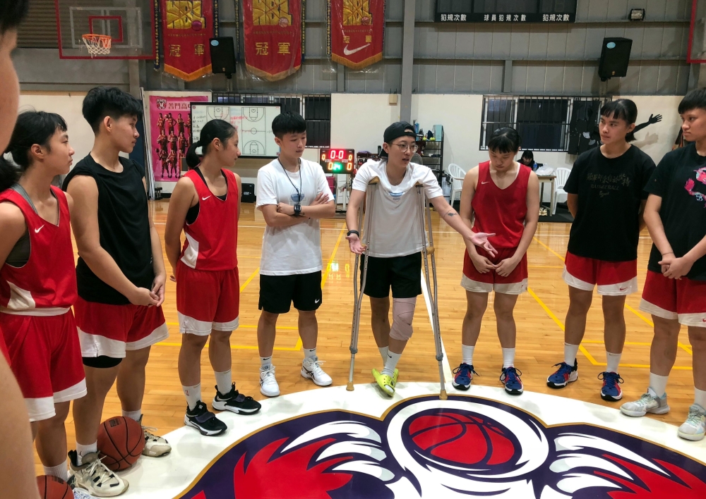 普門女籃總教練李宜瑄（中右）示範動作傷膝仍拄著拐杖精神講話。