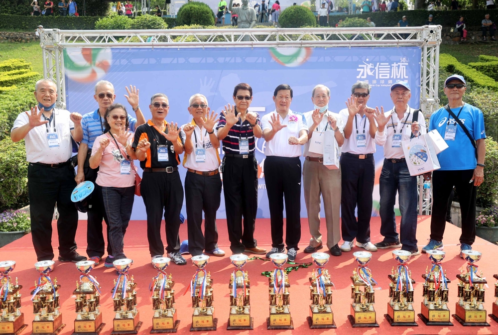 會長李芳裕（右5）和拿過19座永信杯冠軍的新峰男排一起比出永信50手勢。林嘉欣／攝影。