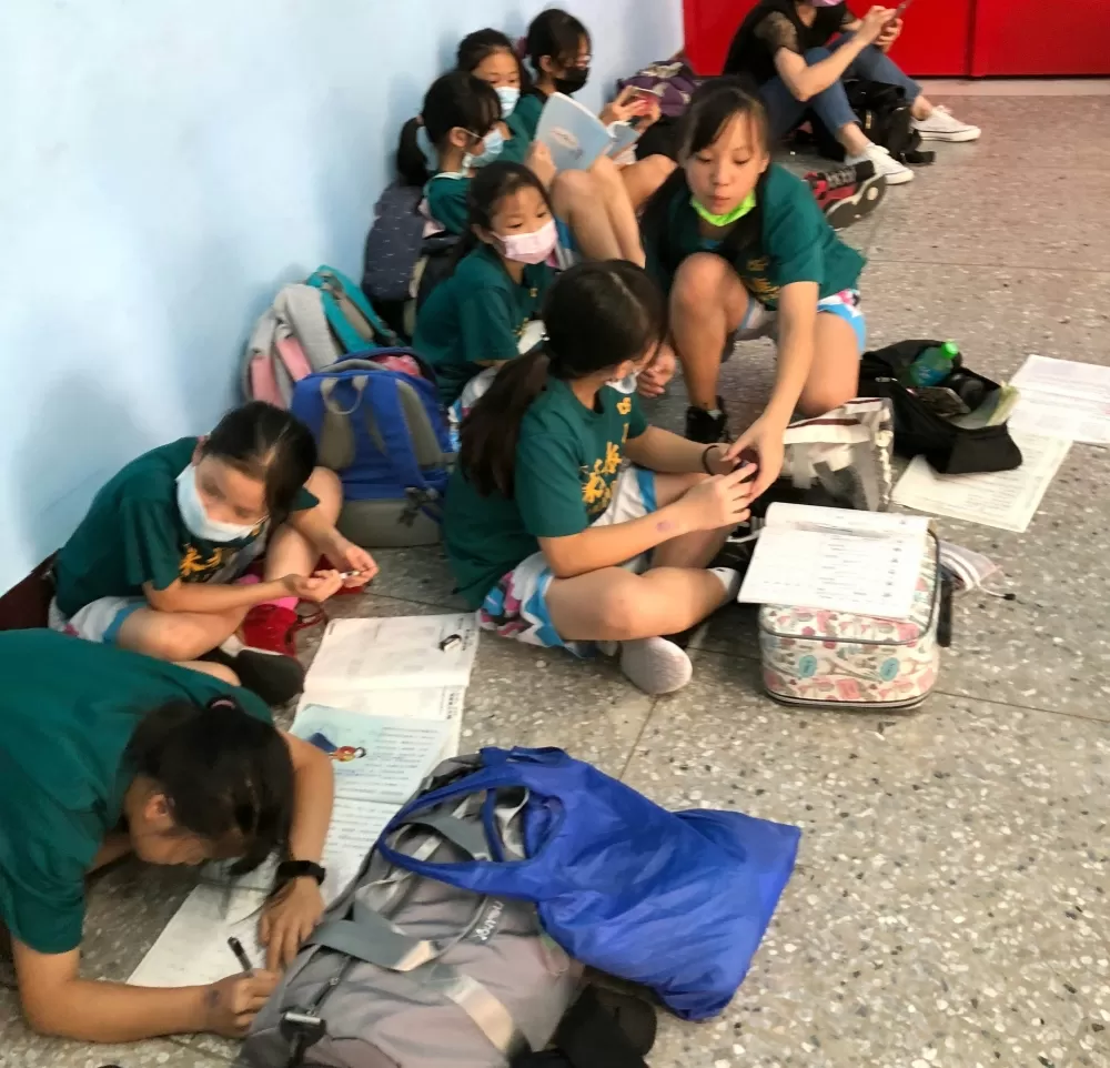 高峰球員集體席地而坐包包打開，課本、作業簿一攤，就地溫習功課。大會提供。