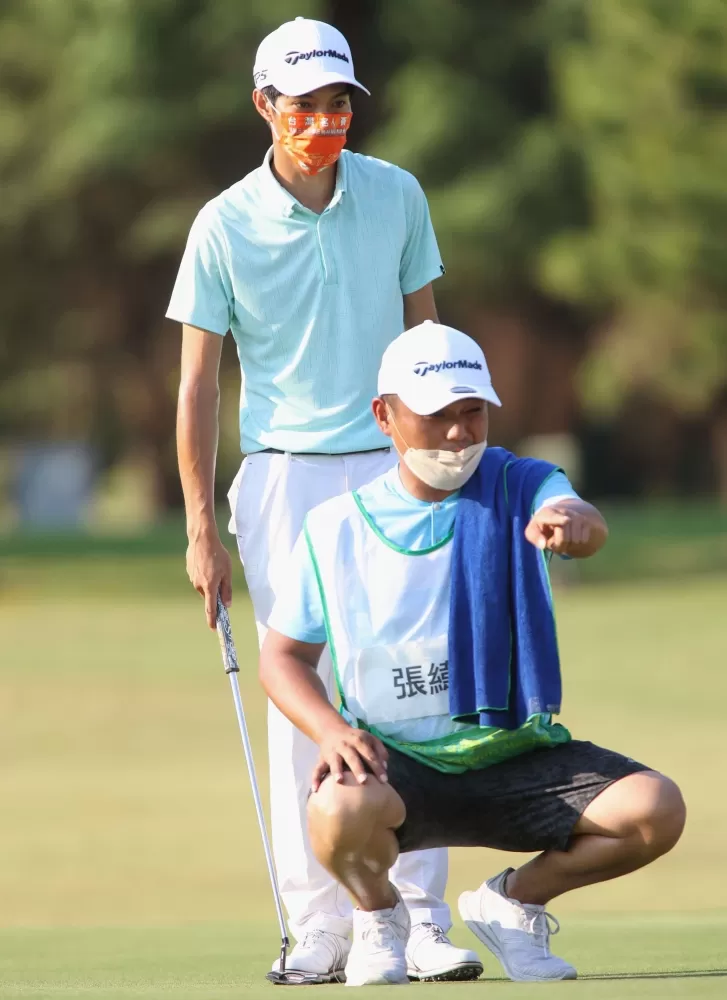 張緯綸(後)與桿弟在果嶺上判讀推桿路線。