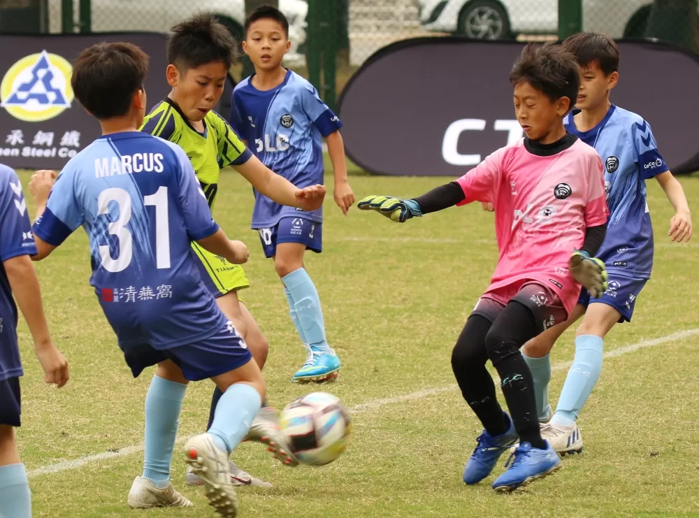 天母國小球員在PLCFA球員包圍下起腳攻門（大會提供）