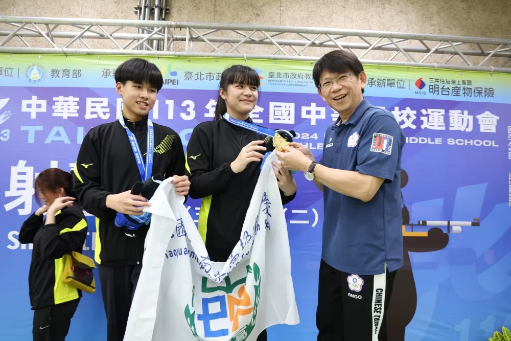 桃園市南崁高中陳星菲(中)與吳學仲聯手贏得射擊高中10公尺空氣步槍混合金牌，接受校長頒贈獎牌。（臺北市政府教育局提供）